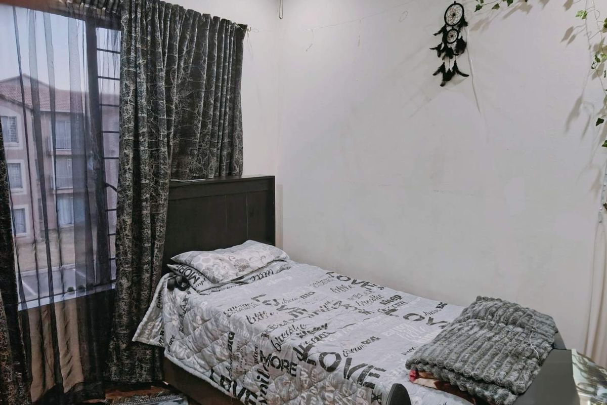A standard bedroom featuring a window with security bars and neutral wall finishes, offering a functional space for rest.
