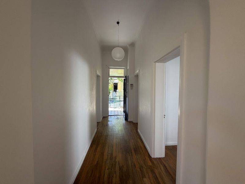 A bright and spacious hallway featuring polished hardwood flooring and neutral walls, providing a clean transition between the home's various rooms.
