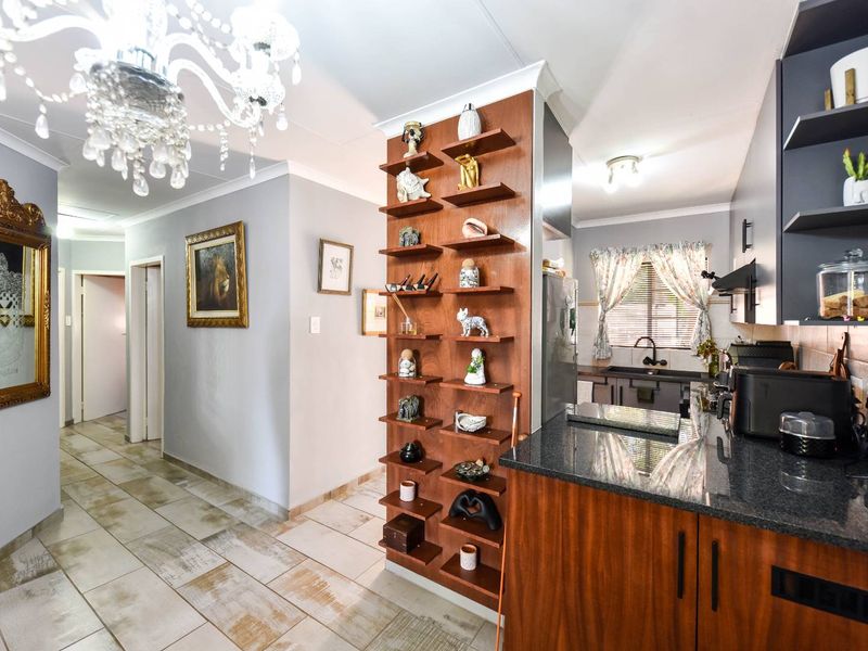 Open plan kitchen and hallway area featuring granite countertops, dark wood cabinetry, and tiled flooring, creating a functional and connected living space.