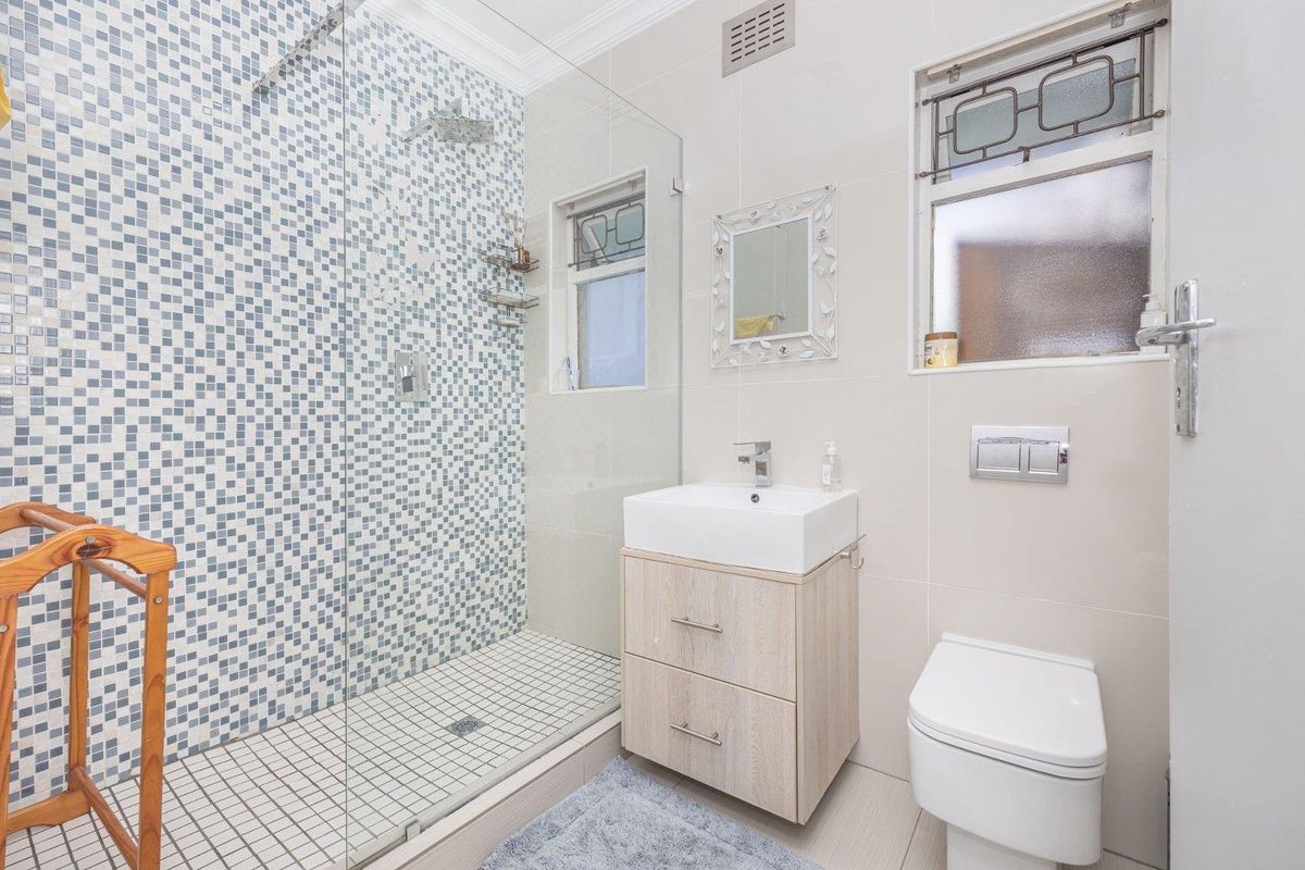 Modern bathroom featuring a walk-in shower with mosaic tiling, a contemporary vanity with basin, and a wall-mounted toilet with a concealed cistern.