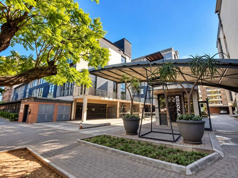 Modern apartment complex entrance featuring a paved driveway, covered canopy, and well-maintained landscaped areas with contemporary architectural finishes.