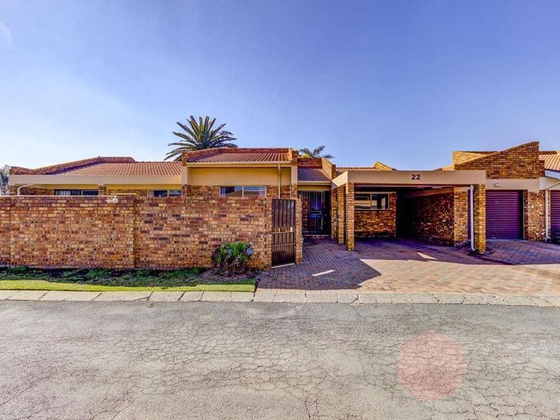 Front elevation of a face brick cluster home featuring a paved driveway, covered carport, and secure gated entrance.