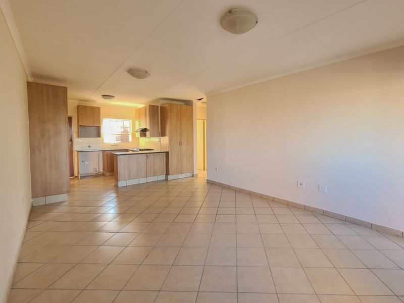 Spacious open-plan living area featuring tiled flooring and an integrated kitchen with built-in cabinetry, hob, and extractor fan.