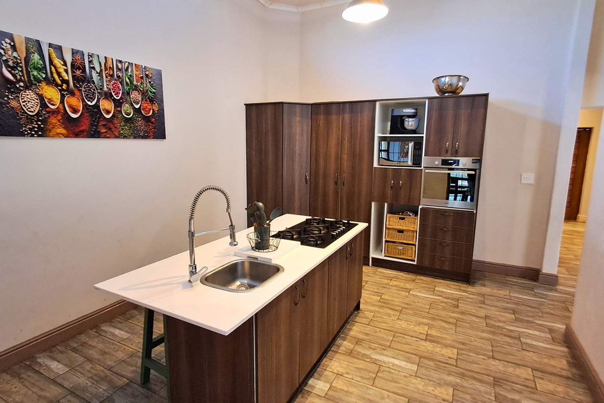 Modern kitchen featuring a central island with a built-in gas hob and stainless steel sink, complemented by dark wood cabinetry and integrated appliances.