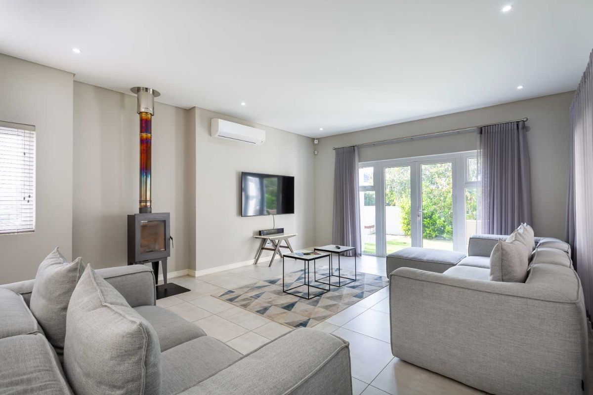 Spacious living room featuring a modern freestanding fireplace, split-system air conditioning, tiled floors, and direct access to the garden through double glass doors.