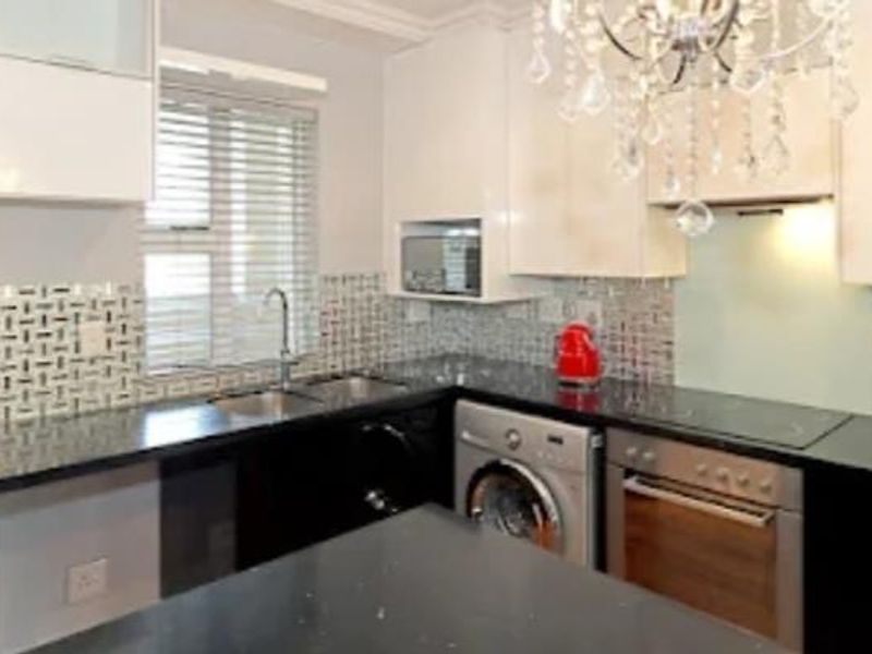 Modern kitchen featuring high-gloss cabinetry, granite countertops, mosaic tile backsplash, and integrated stainless steel appliances including an oven and hob.