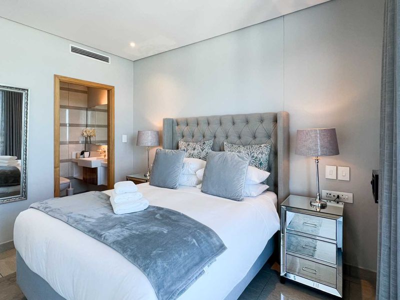 A well-maintained bedroom featuring tiled flooring, ducted air conditioning, and direct access to an en-suite bathroom.