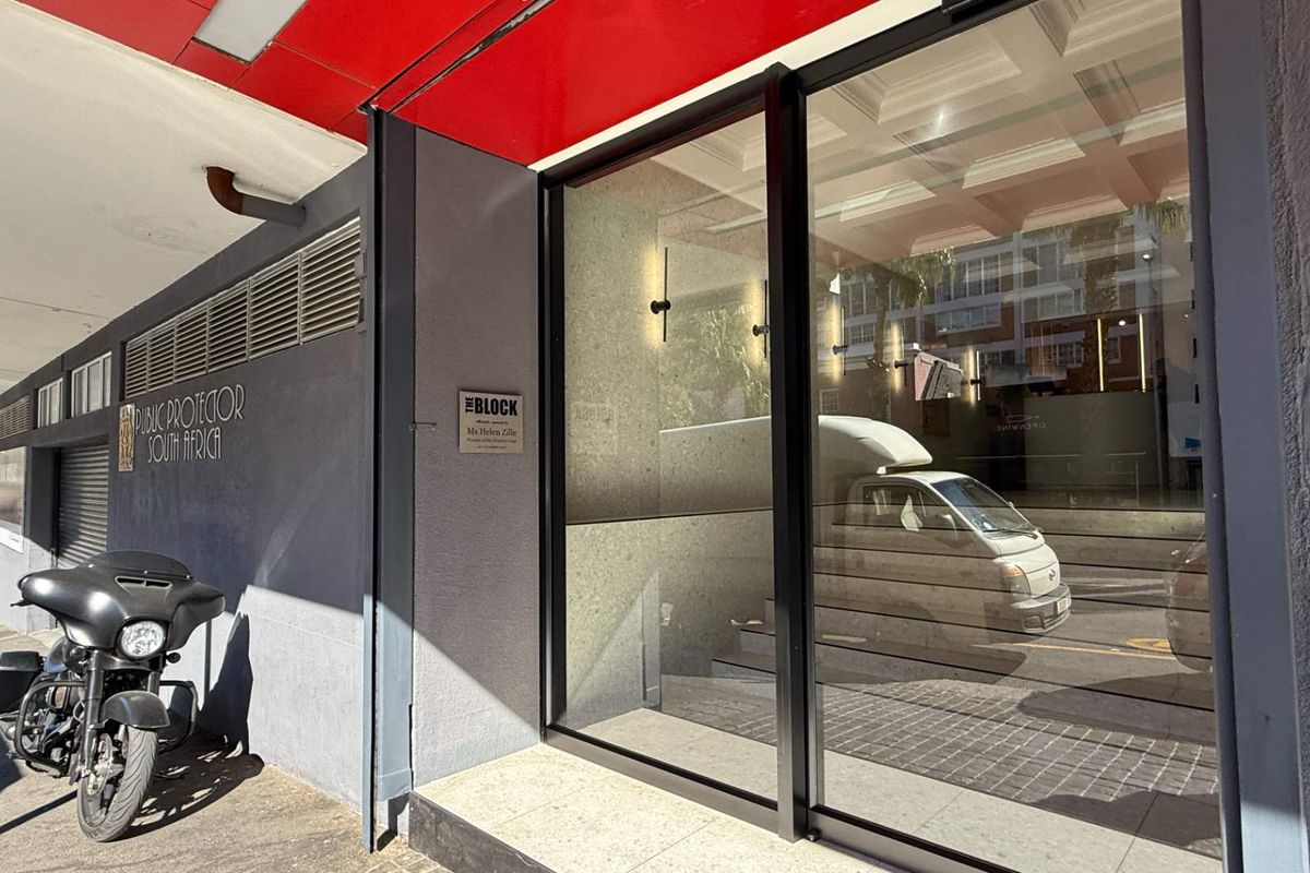 Front entrance of the office building featuring large glass sliding doors and modern signage under a covered walkway.
