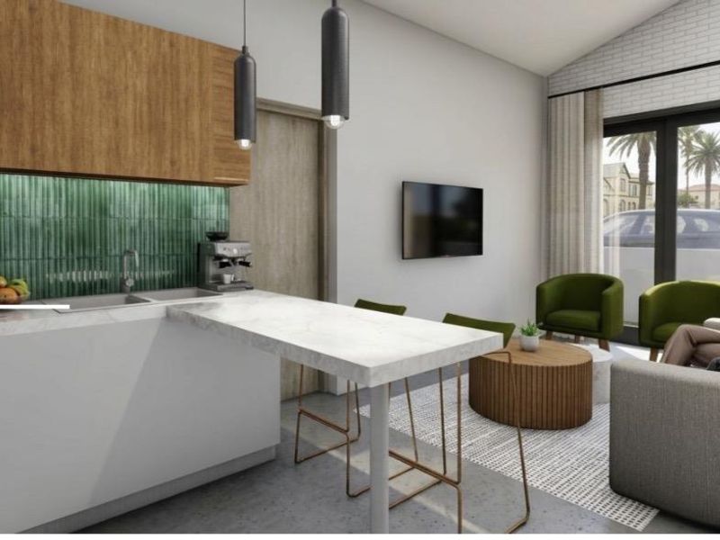 Modern open-plan living area featuring a contemporary kitchen with stone countertops, green tiled backsplash, and seamless flow to the outdoor patio area.