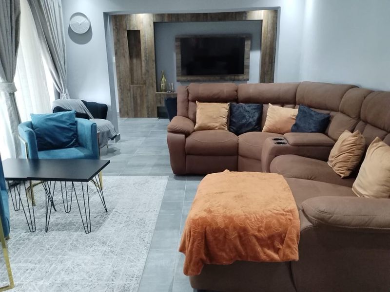 A modern living room featuring large format floor tiles and a custom built-in media wall with integrated shelving and television mount.