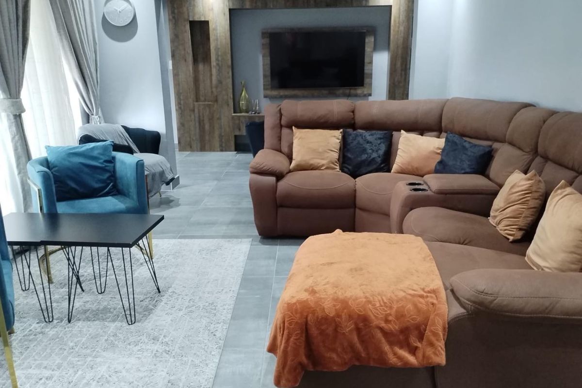 A modern living room featuring large format floor tiles and a custom built-in media wall with integrated shelving and television mount.