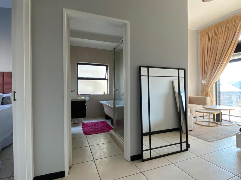 A view from the hallway looking into a bathroom with a bathtub and shower, with adjacent living area visible.