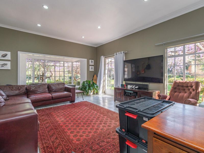 Spacious living room featuring tiled flooring, recessed downlighting, and large windows providing ample natural light and garden views.