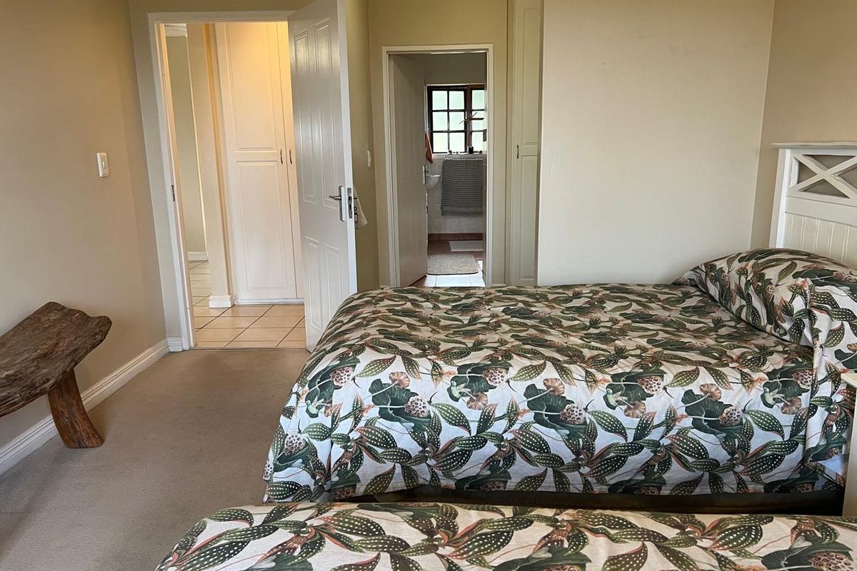 A bedroom featuring built-in cupboards, neutral wall tones, and carpeted flooring, with an adjoining en-suite bathroom visible through the doorway.