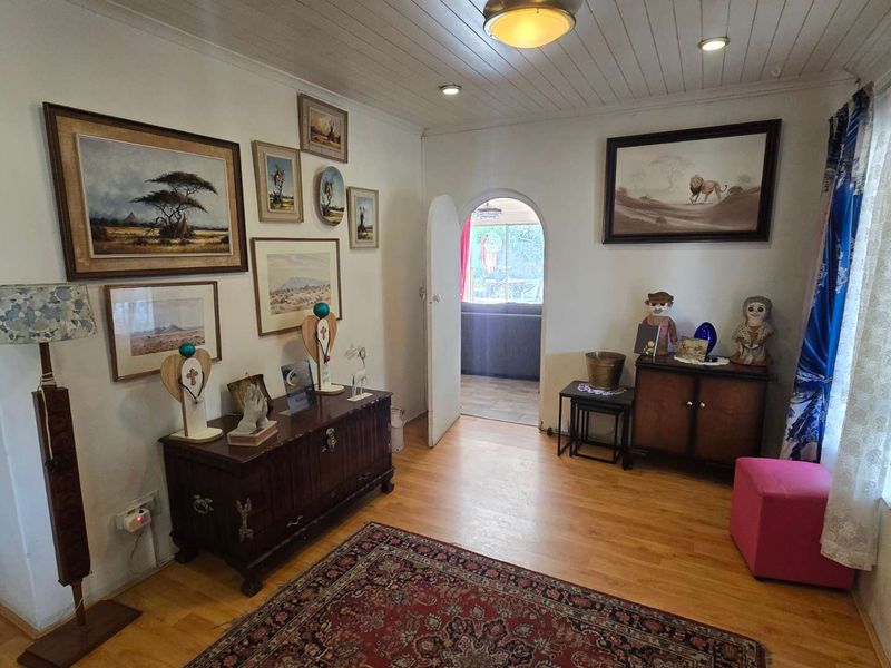 A living room featuring timber tongue and groove ceilings, laminate flooring, and an arched doorway leading to an adjoining space.