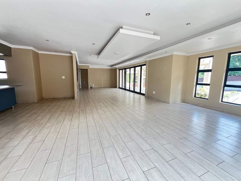 Spacious open-plan living area featuring modern tiled flooring, recessed ceiling lighting, and large aluminium sliding doors leading to the outdoor space.