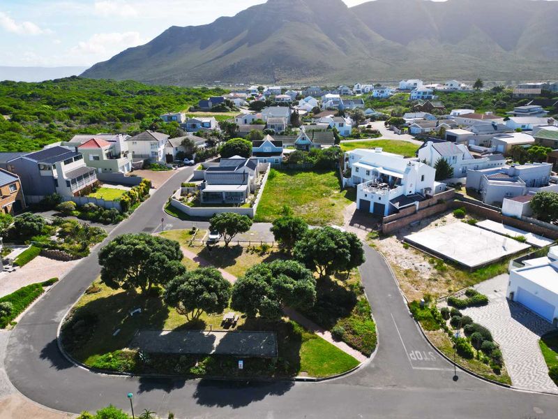 Aerial view of a vacant residential plot situated within an established coastal neighbourhood, featuring mountain views and convenient access to local infrastructure.