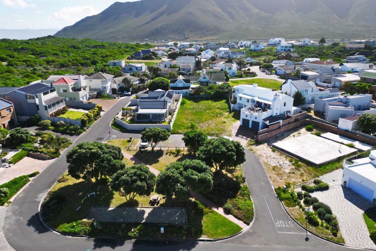 Aerial view of a vacant residential plot situated within an established coastal neighbourhood, featuring mountain views and convenient access to local infrastructure.