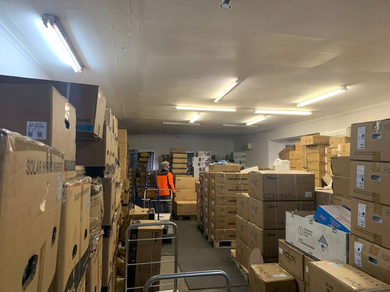 A utility or storage space featuring fluorescent lighting and an air conditioning unit, currently utilized for inventory storage.