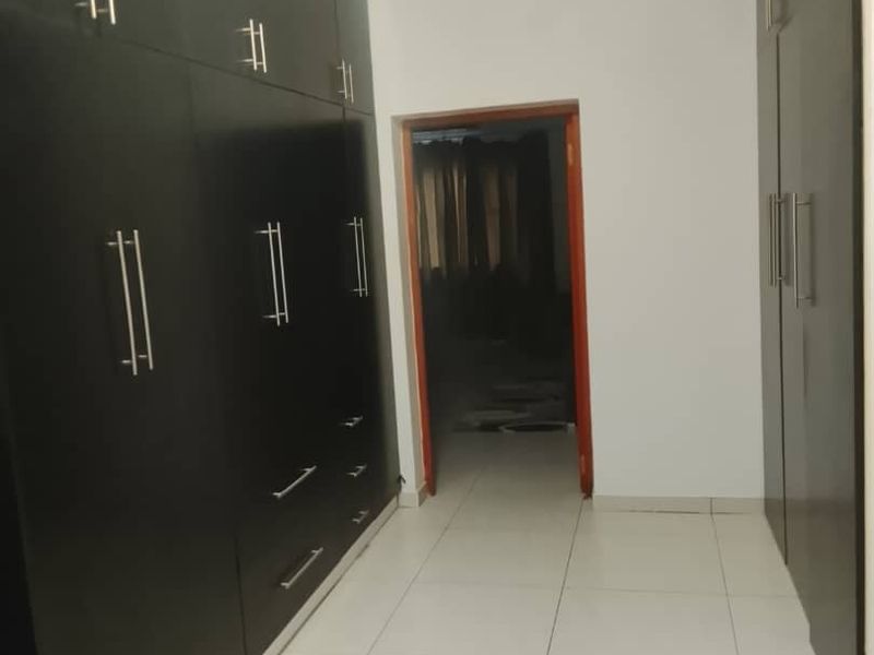 A clean, empty bedroom featuring extensive dark built-in cupboards and neutral tiled flooring, offering a versatile space ready for personalization.