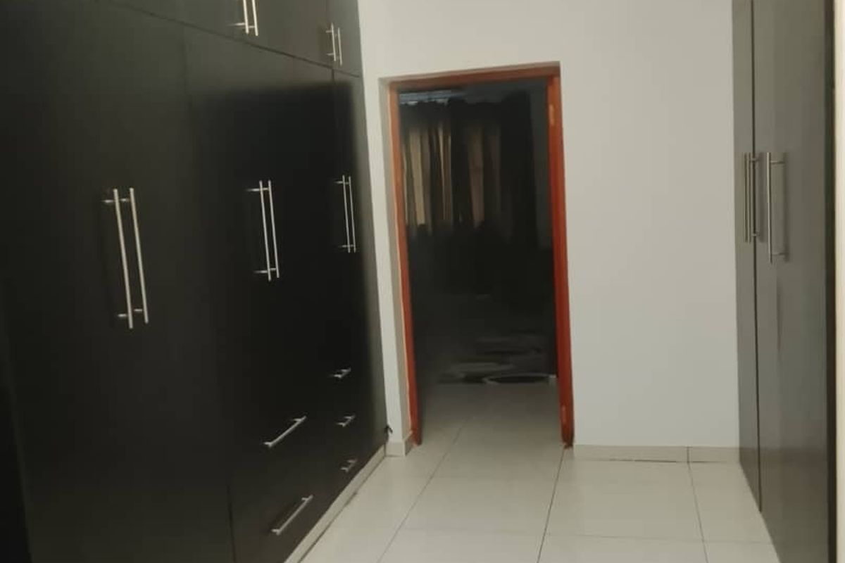 A clean, empty bedroom featuring extensive dark built-in cupboards and neutral tiled flooring, offering a versatile space ready for personalization.