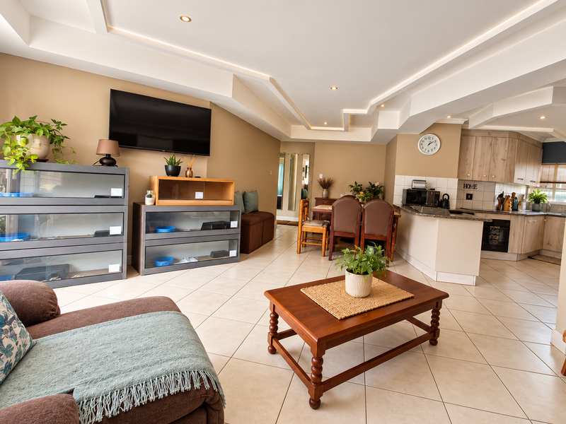 Spacious open-plan living and kitchen area featuring tiled flooring, a modern coffered ceiling with recessed lighting, and functional built-in kitchen cabinetry.