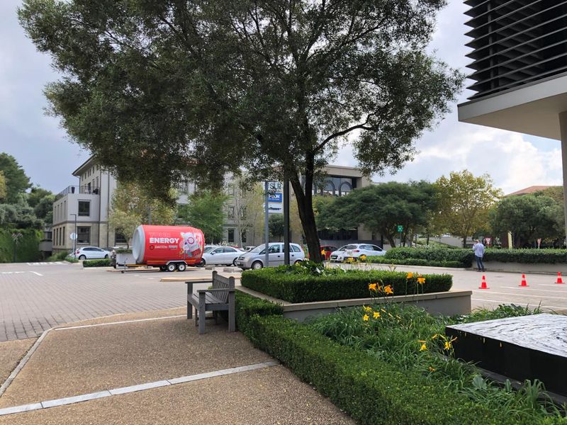 A well-maintained office exterior featuring paved walkways, landscaped garden beds, and a water feature in a professional business park setting.