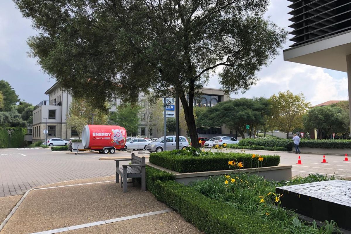A well-maintained office exterior featuring paved walkways, landscaped garden beds, and a water feature in a professional business park setting.