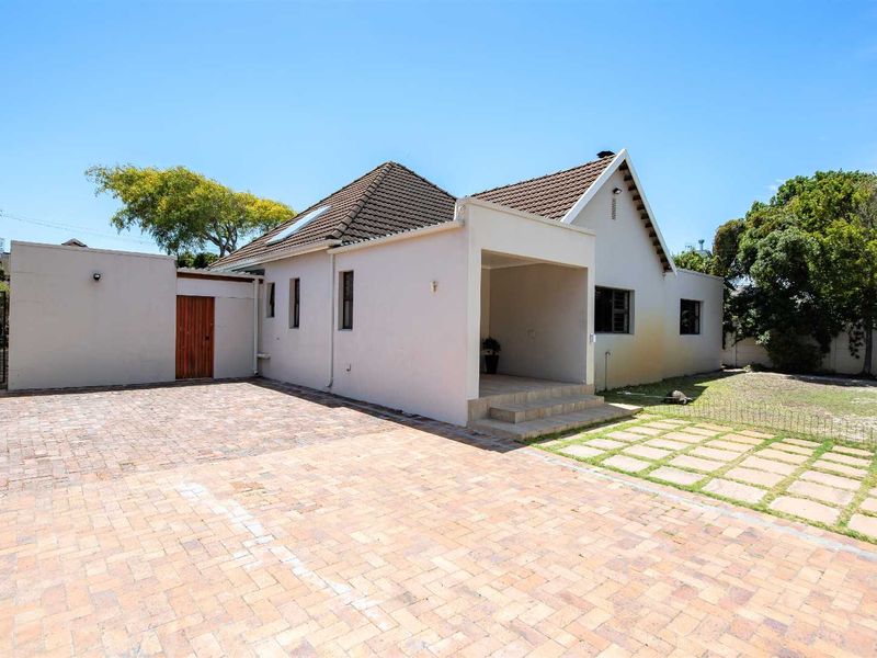 Front exterior view of a house featuring a paved driveway, covered entrance, and a small garden area with a boundary wall.