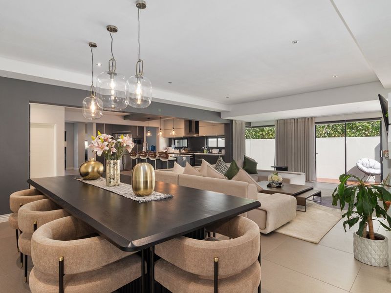 Spacious open-plan living and dining area featuring modern tiled floors, contemporary pendant lighting, and seamless flow to the outdoor patio through sliding glass doors.