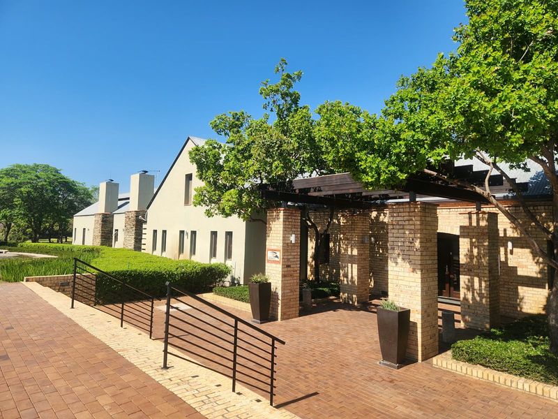 A well-maintained front exterior featuring brick paving, a timber pergola, and established landscaping leading to the building entrance.