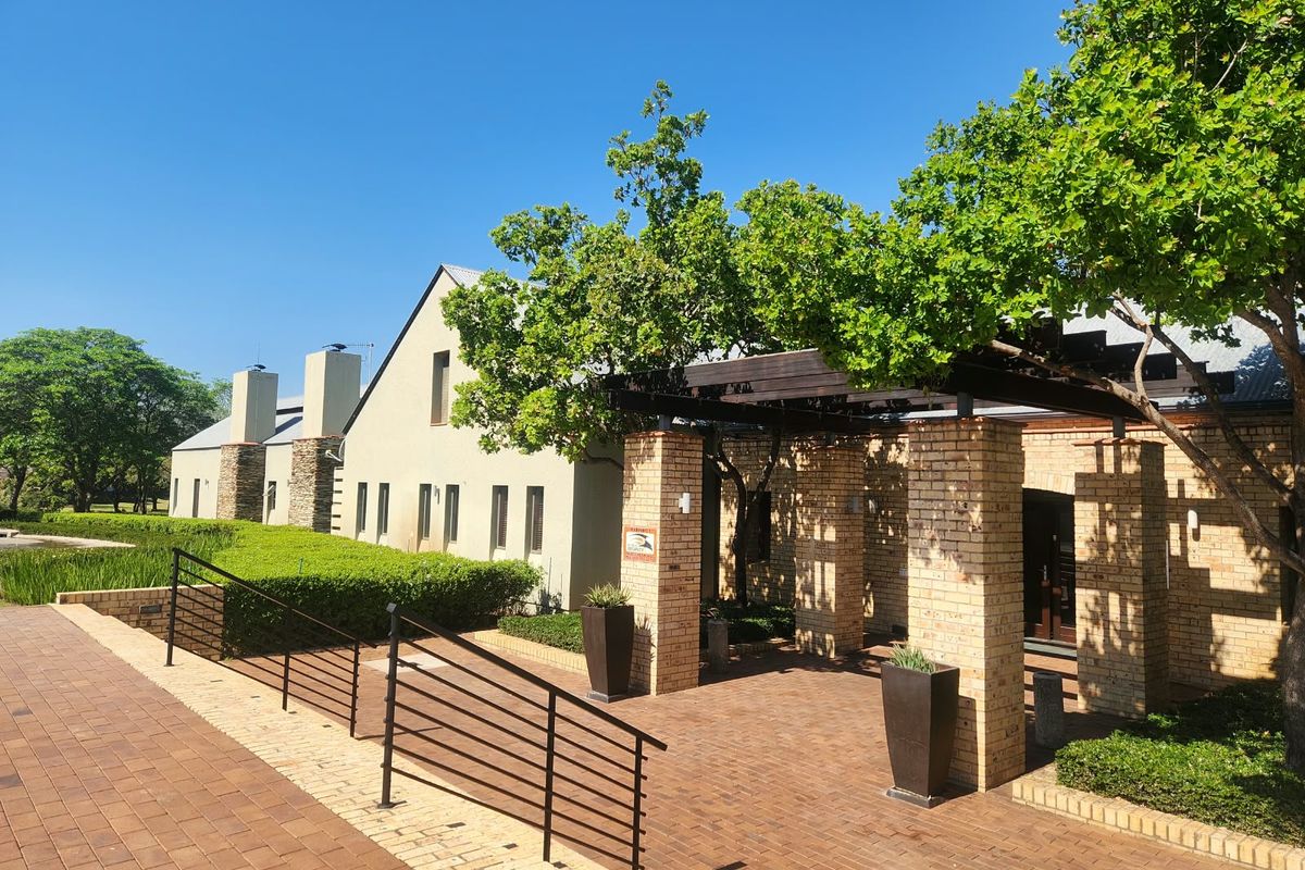 A well-maintained front exterior featuring brick paving, a timber pergola, and established landscaping leading to the building entrance.