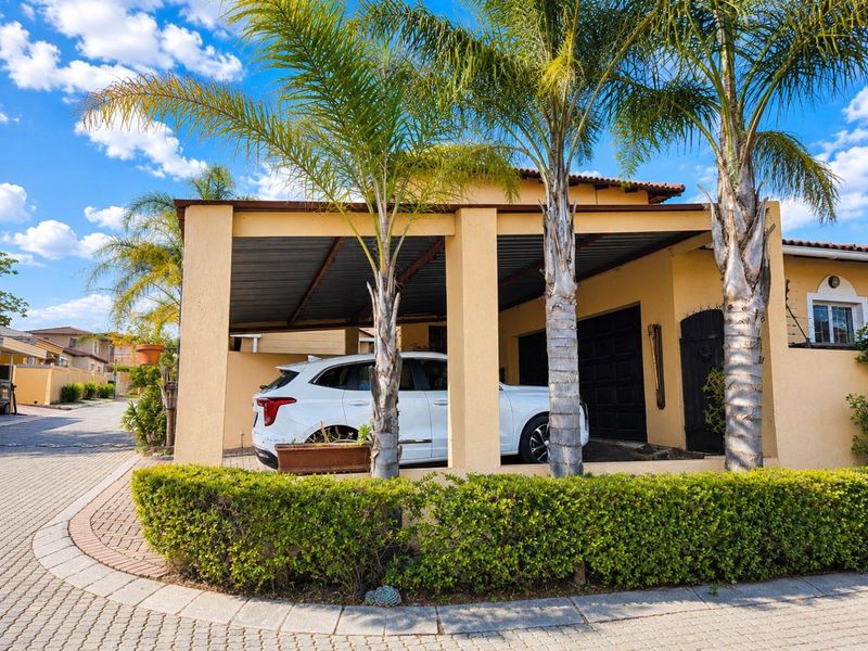 Front exterior view of the property featuring a covered carport, paved driveway, and established garden landscaping.