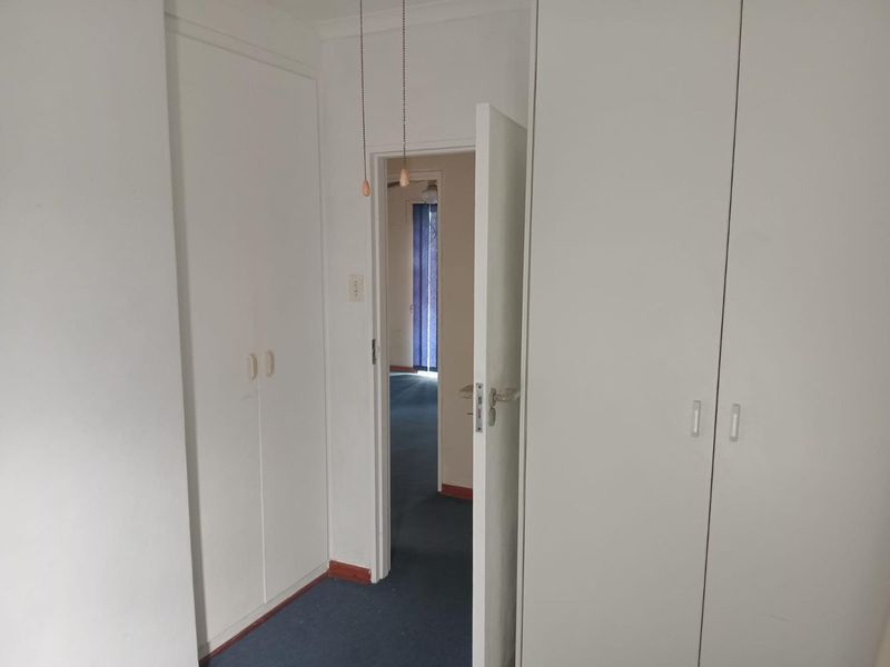 A functional hallway featuring built-in storage cupboards and access to adjacent rooms, finished with carpeted flooring.