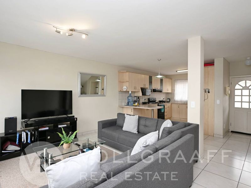 Open-plan living area featuring a functional kitchen with built-in cabinetry and tiled flooring, seamlessly connected to the main living space.