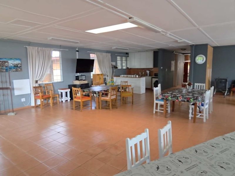 Spacious open-plan living and kitchen area featuring tiled flooring and a drop ceiling, offering a versatile layout for dining and relaxation.