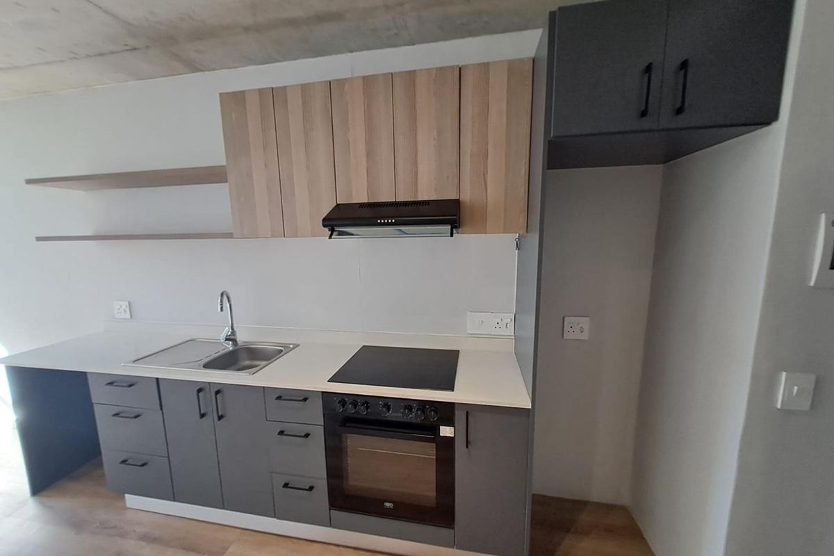 Modern kitchen featuring two-tone cabinetry, built-in oven, electric hob, extractor fan, stainless steel sink, and floating shelves with an exposed concrete ceiling.