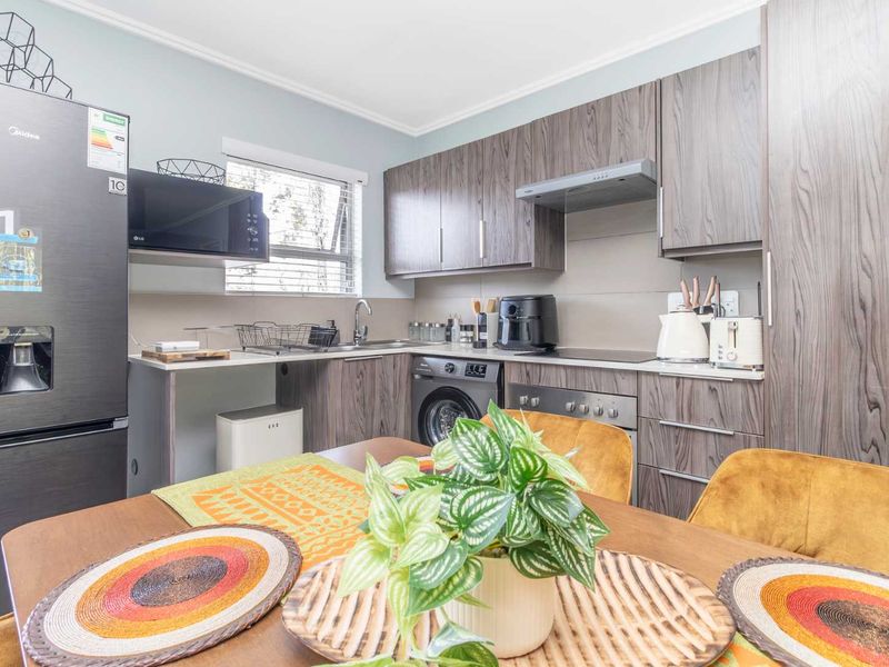 Modern open-plan kitchen featuring wood-grain cabinetry, integrated appliances, and a functional layout, seamlessly connecting to the dining area.