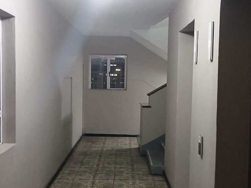 A functional apartment building hallway featuring tiled flooring, access to a staircase, and an elevator.