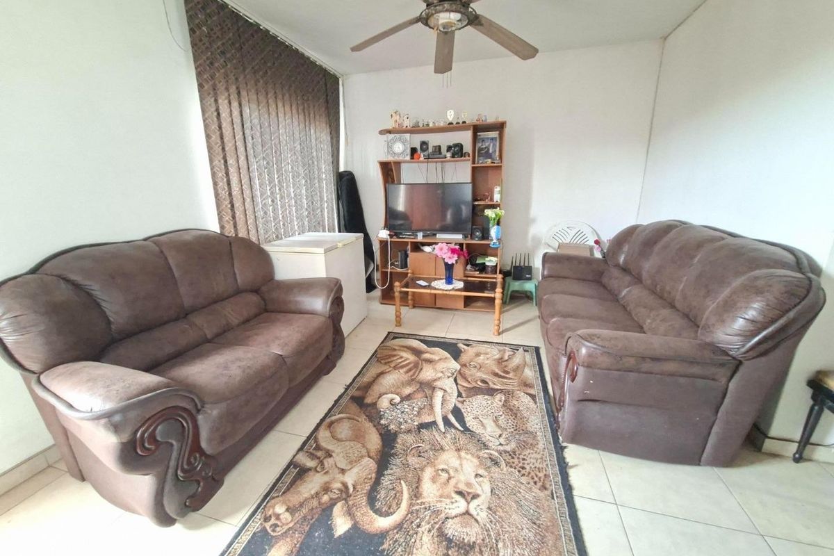 A living room featuring tiled flooring, a ceiling fan, and vertical blinds, offering a functional space for relaxation.