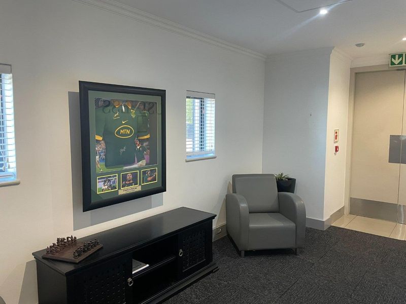 A professional office space featuring neutral walls, recessed lighting, carpeted flooring, and venetian blinds, providing a clean and functional work environment.