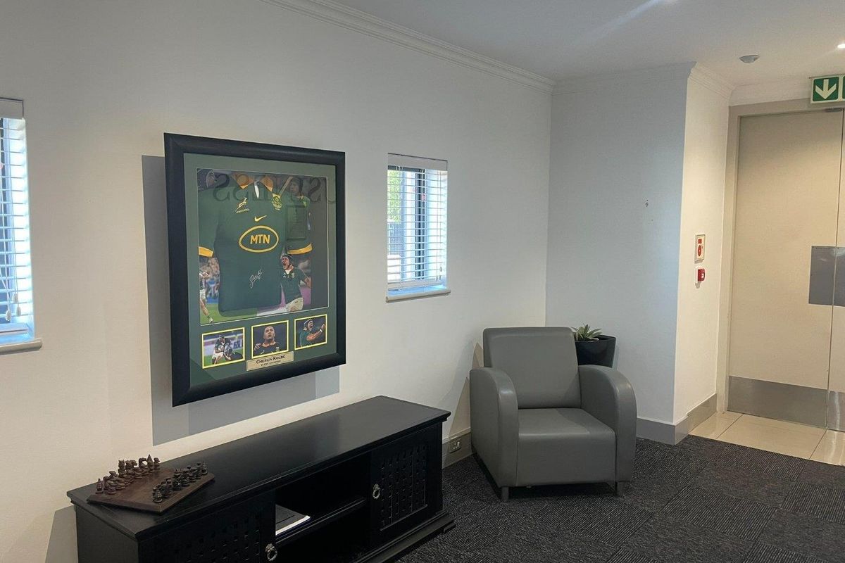 A professional office space featuring neutral walls, recessed lighting, carpeted flooring, and venetian blinds, providing a clean and functional work environment.