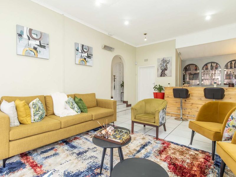 A spacious living area featuring a built-in bar, tiled flooring, and an arched entryway, offering a versatile space for relaxation and entertaining.