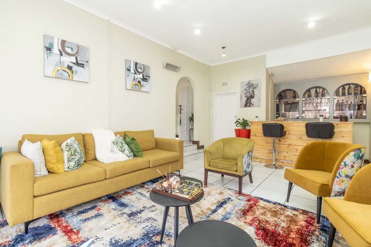 A spacious living area featuring a built-in bar, tiled flooring, and an arched entryway, offering a versatile space for relaxation and entertaining.