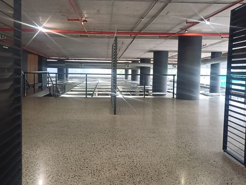 A spacious, modern open-plan retail or commercial area featuring polished concrete floors, exposed industrial ceilings, and structural columns with contemporary metal screening.