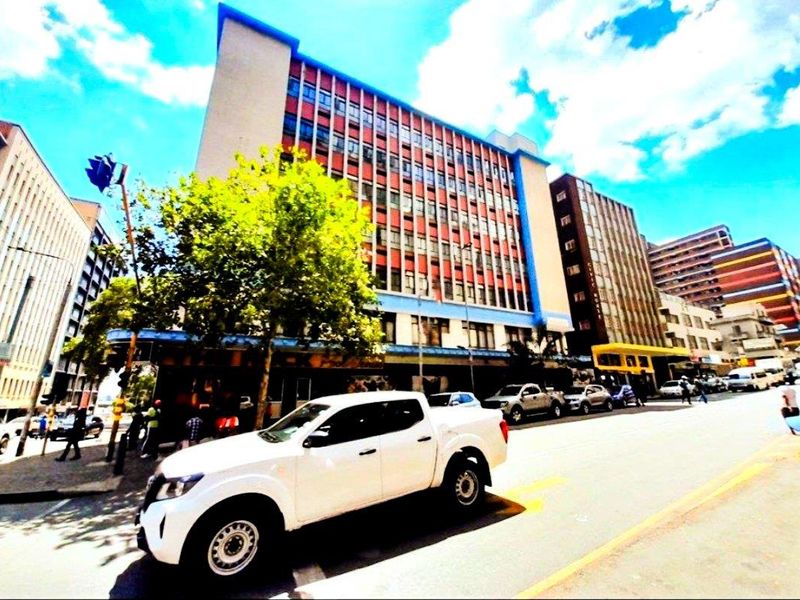 Street-level view of a multi-story apartment building featuring commercial ground floor space in an urban setting.