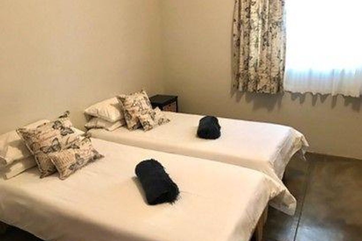 A functional bedroom featuring tiled flooring and a window with curtains, providing a simple and comfortable sleeping space.