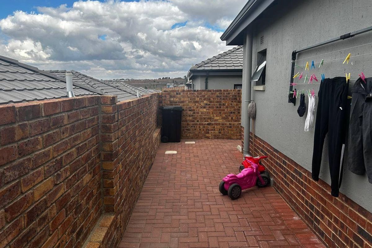 A side exterior area featuring brick paving, a perimeter brick boundary wall, and a wall-mounted clothes drying line.