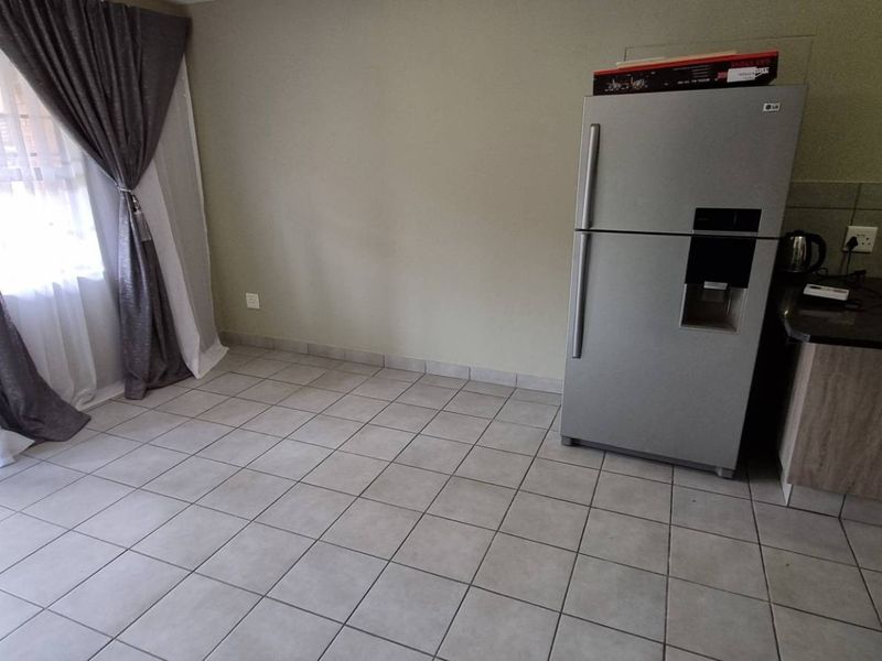 Open plan living and kitchen area featuring tiled flooring, granite countertops, and direct access to the outdoors via a sliding door.