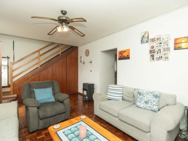Living room featuring classic parquet flooring, a ceiling fan, and integrated under-stair storage cabinetry.